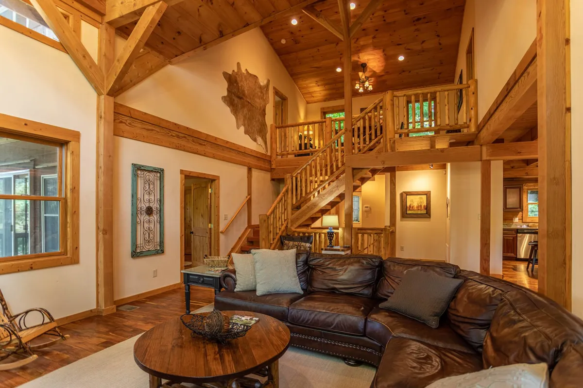 A cozy living area with a leather sofa, wooden staircase, decorative wall art, and a round coffee table. The space is arranged for family relaxation and socializing, evoking warmth and comfort—perfect for unwinding after a day of mountain exploration.