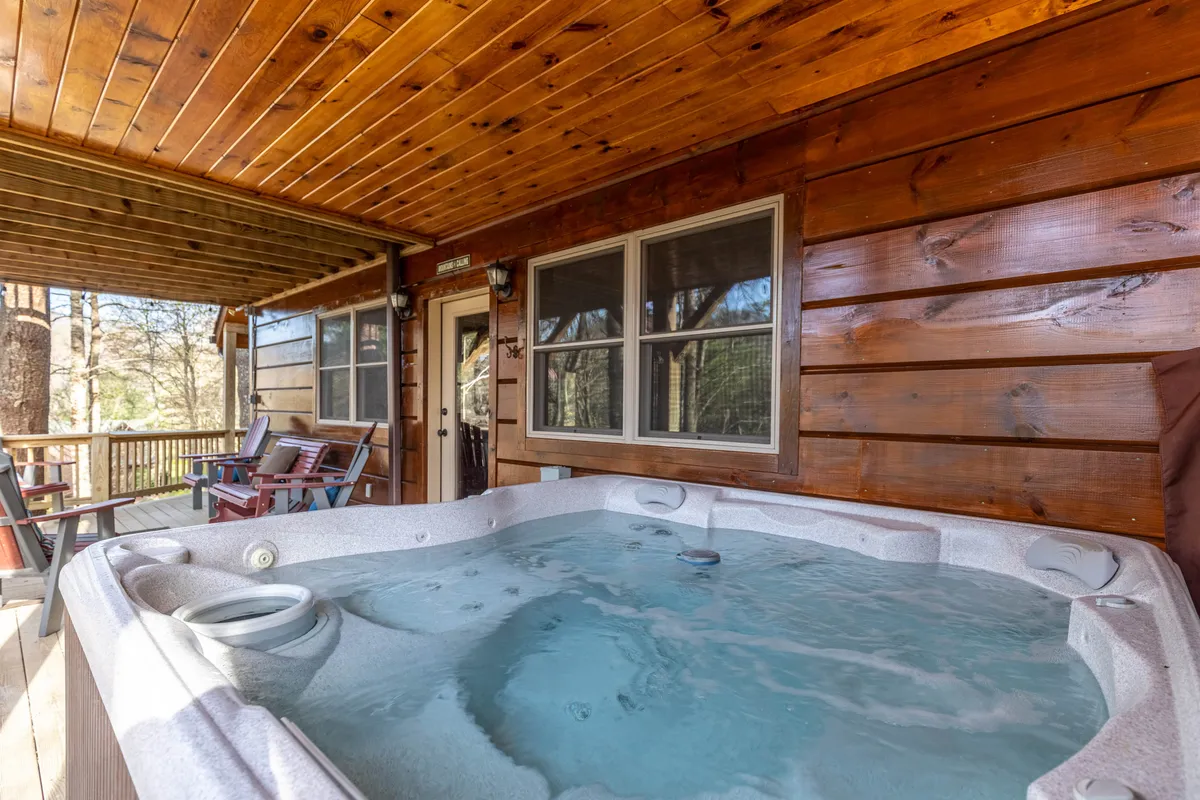 An inviting indoor hot tub is set beneath a wooden ceiling and surrounded by panoramic windows, offering views of the lush outdoors. The space is designed for relaxation, making it ideal for unwinding at any time of day while remaining immersed in the natural landscape.